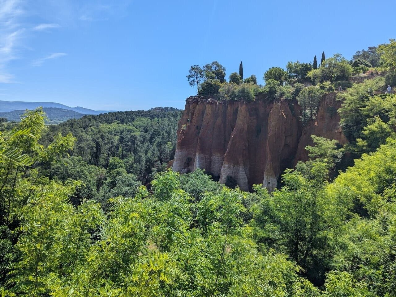 A natural landscape with a prominent rock formation and dense green foliage.