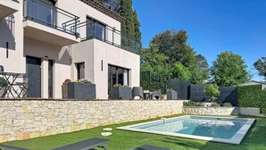 A modern house with a stone wall, a swimming pool, and outdoor furniture. - Comfortable villa with pool, AC and garden in Saint‑Paul‑de‑Vence (Saint Paul de Vence)