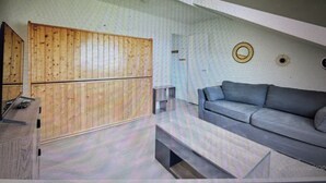 A room with a wooden panel wall, a grey sofa, and a circular wall decoration.