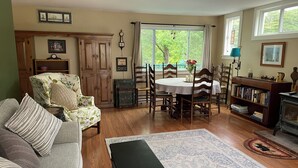 Una sala de estar acogedora con sofá, una mesa de centro, una mesa de comedor con sillas, una estantería y una chimenea.