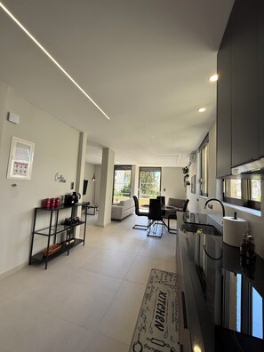 A modern kitchen with a dining area, a coffee bar, and a view of the outdoors. - Welcome to Notos Suites - An Athenian Riviera Stay (Voula)