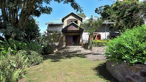 A stone house with a green roof, surrounded by lush greenery and a well-maintained lawn. - Private Pool Villa with Iconic Piton Views (Soufrière)