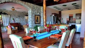 A dining area with a long wooden table, striped chairs, and a stone wall. - Private Pool Villa with Iconic Piton Views (Soufrière)