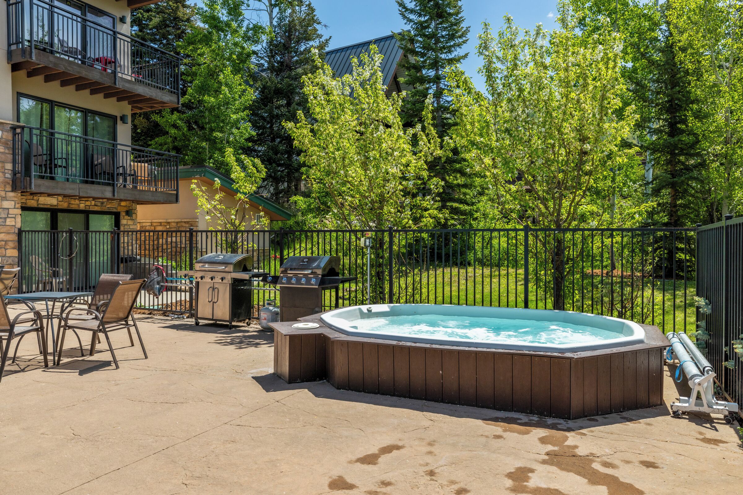 Un jardin avec un jacuzzi, un barbecue et un espace salon extérieur.