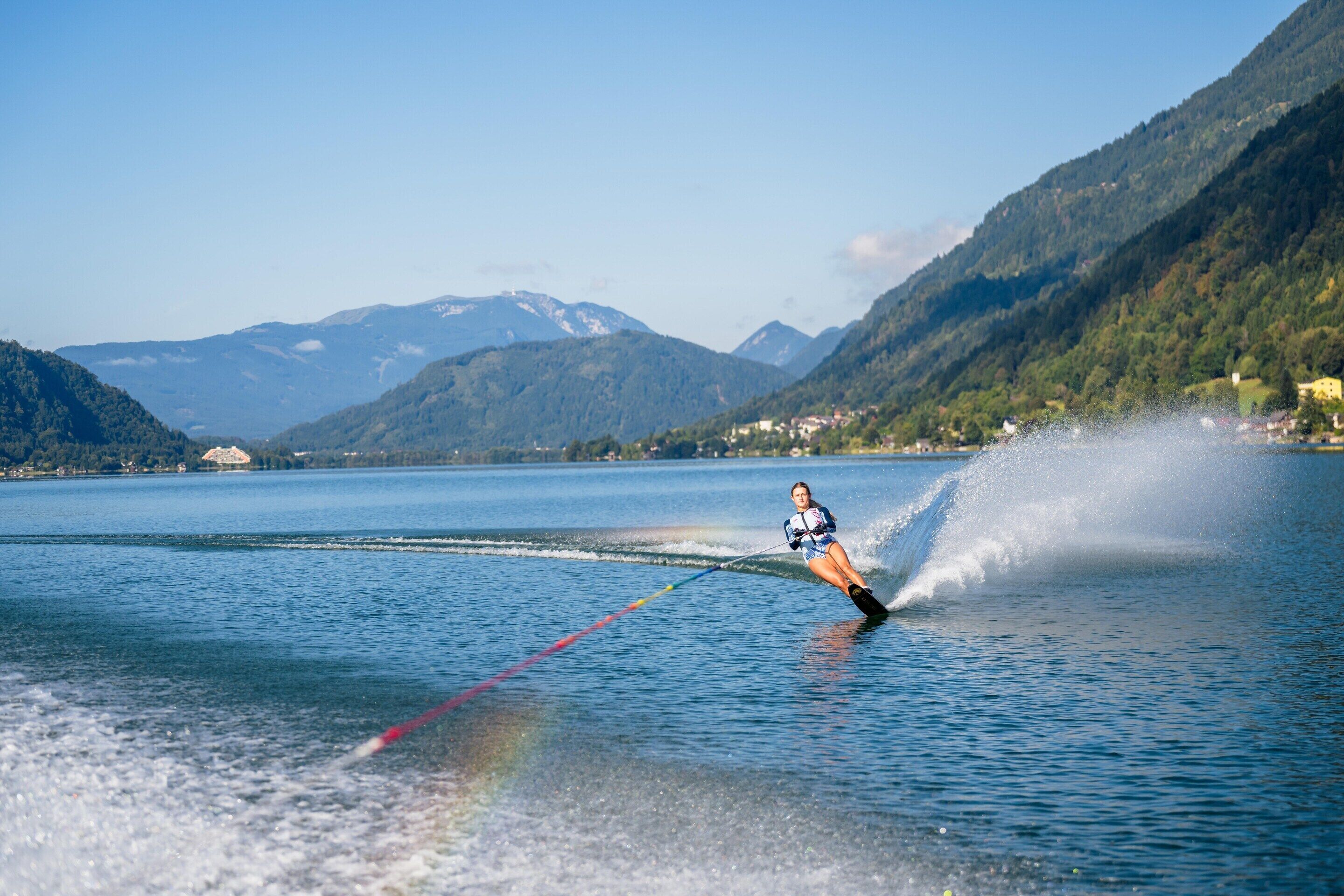 A person water skiing on a lake with mountains in the background.