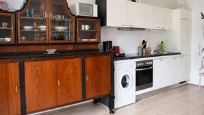 A kitchen with wooden cabinets, a microwave, a washing machine, and a sink. - Panorama Apartment on Lake Ossiach (Steindorf am Ossiacher See)
