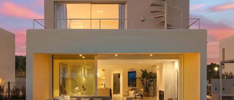 Une maison moderne à deux étages, dotée d’une piscine, d’un espace salon extérieur et d’un escalier.