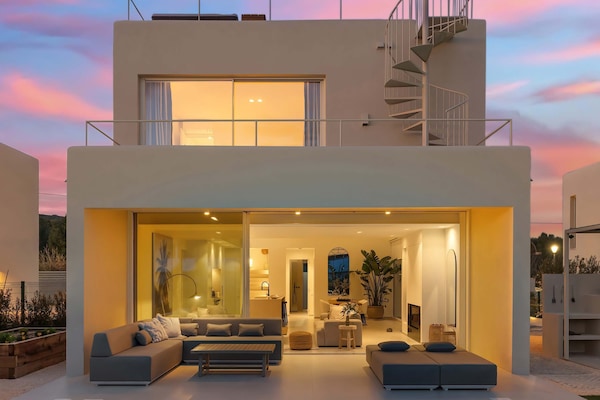The perfect golden-hour ambiance—where indoor and outdoor living blend seamlessly. Relax by the illuminated pool or lounge on the covered terrace as the sun sets, creating a warm and inviting glow over this stunning retreat.”