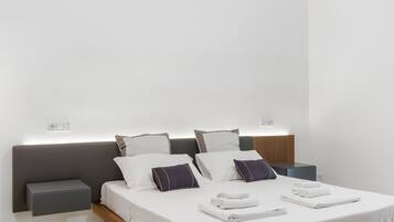 A modern hotel room with a neatly made bed, bedside tables, and a wall-mounted light fixture.