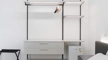 Una habitación minimalista con un escritorio blanco, un mueble pequeño y una cama.