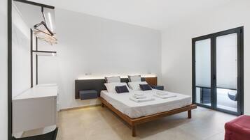 Una camera da letto moderna con un letto, comodini, una scrivania e una porta scorrevole in vetro che dà sull'esterno.