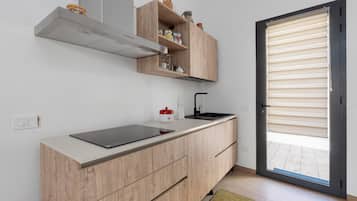 Una cocina moderna con estufa integrada, armarios de madera y una puerta corrediza de vidrio al patio.