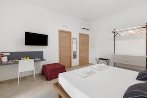 Habitación de hotel con cama, escritorio con silla, televisor, armario y espejo.