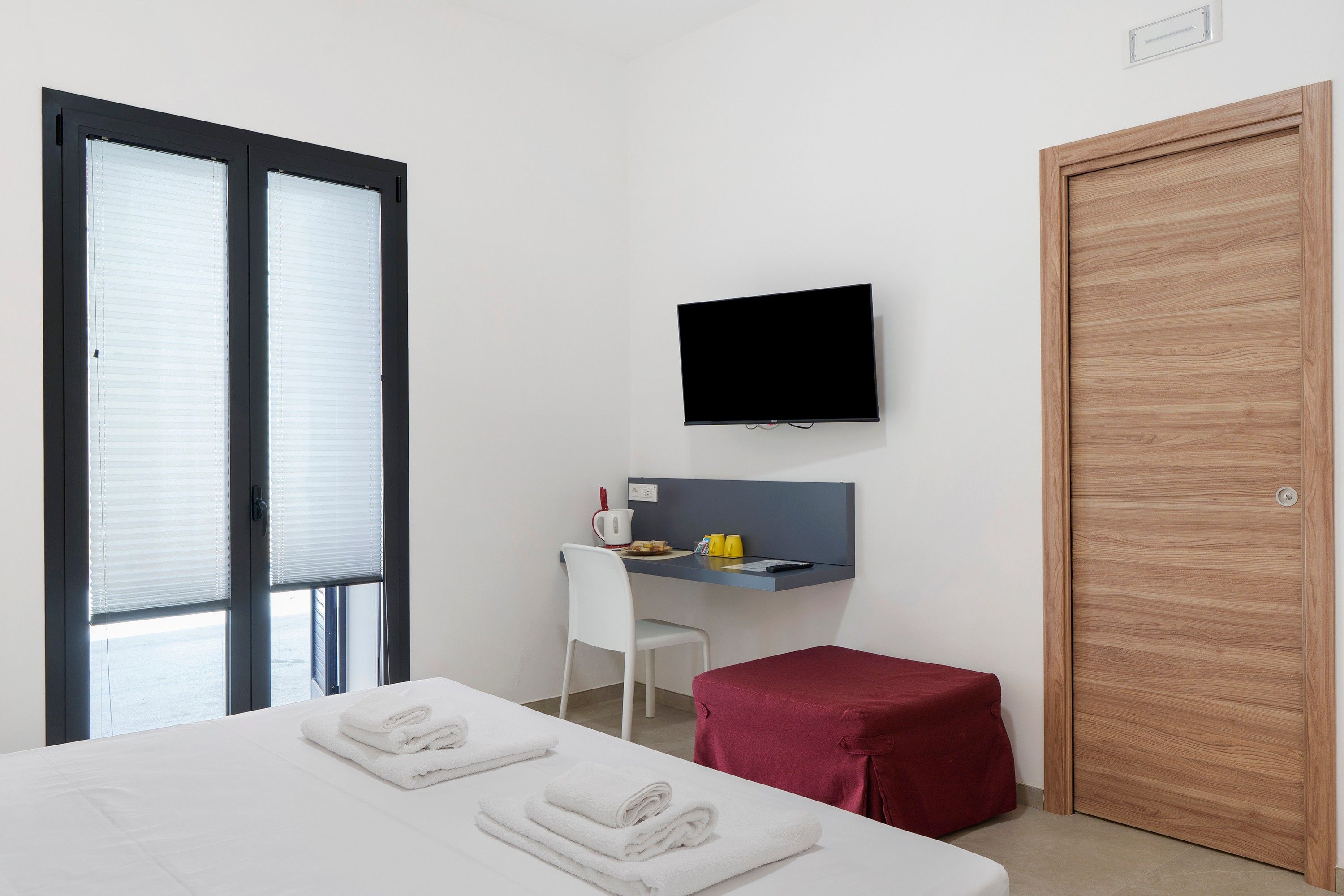 Una habitación de hotel con una cama, un escritorio, un televisor y una puerta de madera.