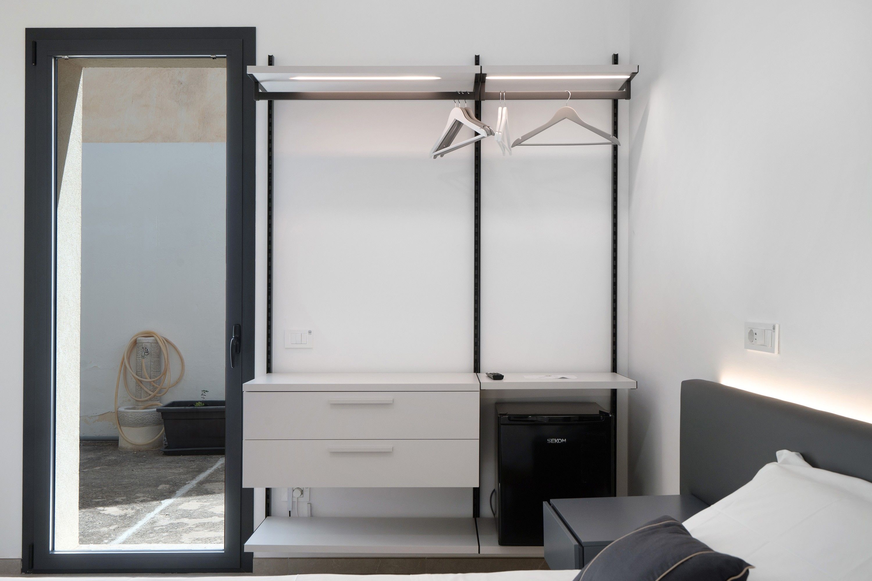 Une chambre à coucher moderne comprenant un lit, un bureau avec une chaise, une armoire et une petite table de chevet.
