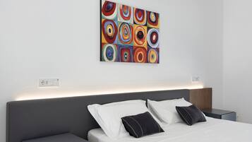 Een moderne hotelkamer met een net opgemaakt bed, een nachtkastje en een wanddecoratie.