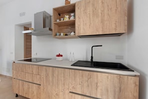 Una cocina moderna con armarios de madera, un lavamanos de acero inoxidable y un horno empotrado.