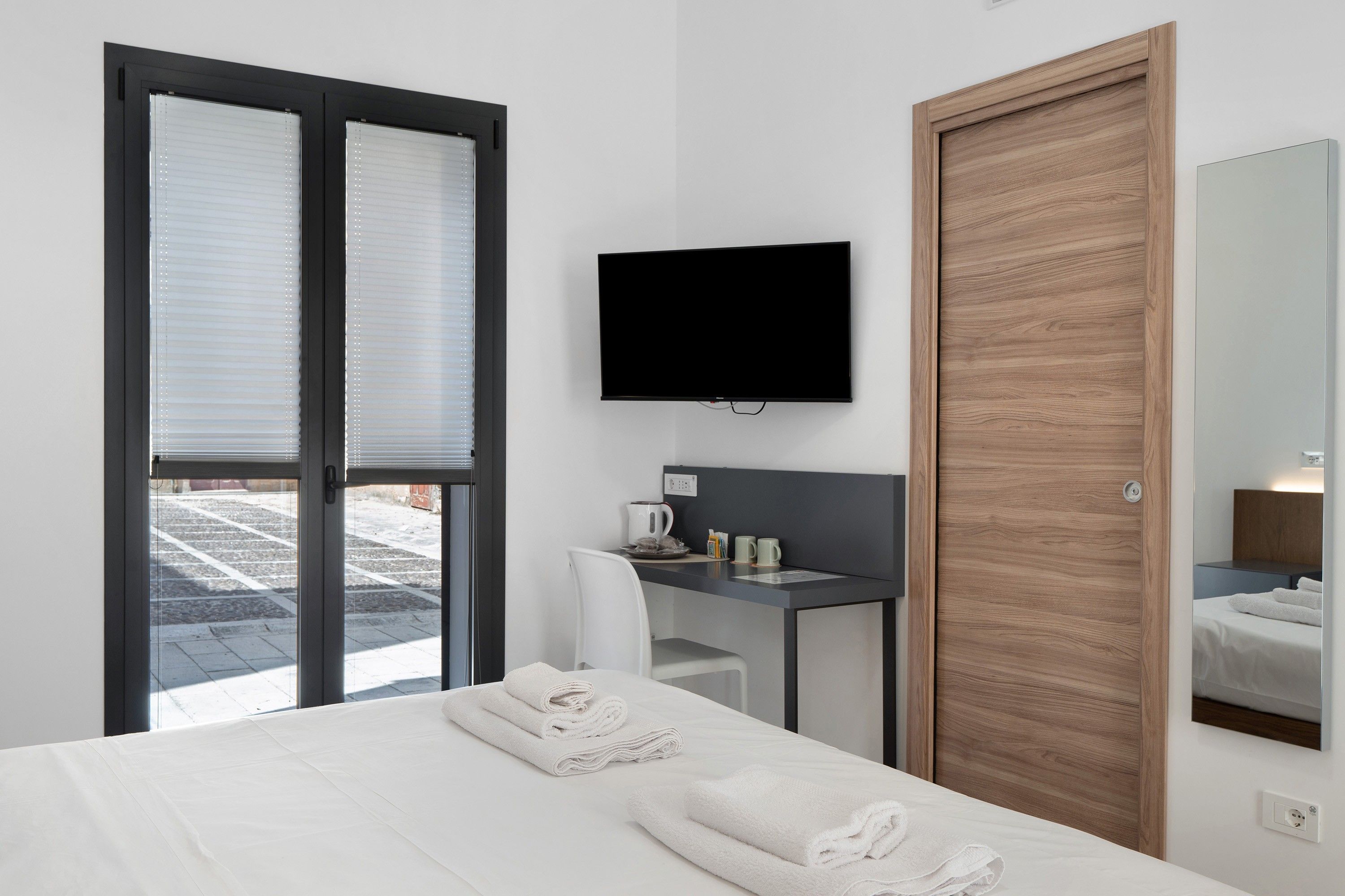 A hotel room with a bed, a desk, a television, and a mirror.