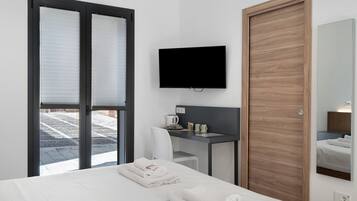 A hotel room with a bed, a desk, a television, and a mirror.
