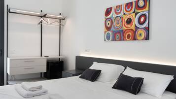 Una habitación de hotel moderna con una cama, una mesita de noche, una obra de arte en la pared y un armario.
