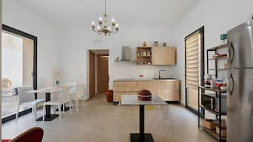 A modern kitchen with a dining area, a chandelier, and a refrigerator.