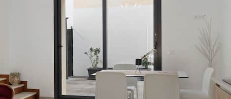 A dining area with a table and chairs, a sliding glass door leading outside, and a potted plant.