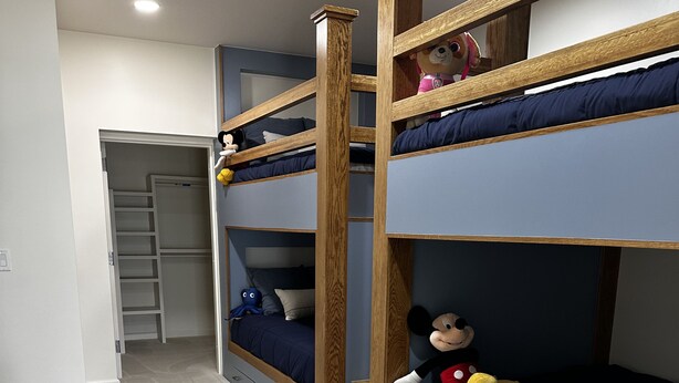 Ein Schlafzimmer mit Etagenbett aus Holz, einem Schrank mit Leiter und Teppichboden.