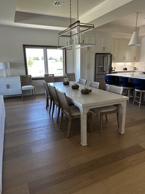 A spacious kitchen with a large island, wooden flooring, and white cabinetry.