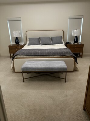 Une chambre à coucher avec un lit, des tables de chevet, des lampes et un banc.