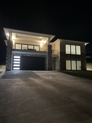 A two-story house with a garage, stone pillars, and large windows.