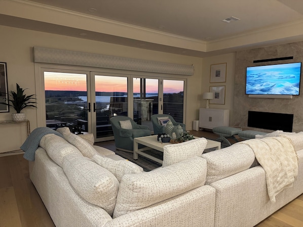 A living room with a large sofa, a coffee table, and a television mounted on the wall.