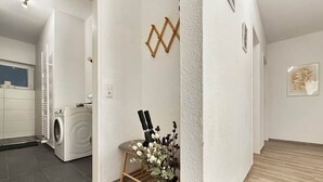 Un interior moderno con lavadora, suelo de madera y un adorno en la pared.