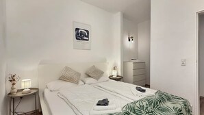 Una habitación de hotel con cama, mesitas de noche, cómoda y lámpara de pared.