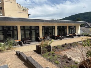 Een gebouw met een overdekt terras, buitenplanten en een grindpad.