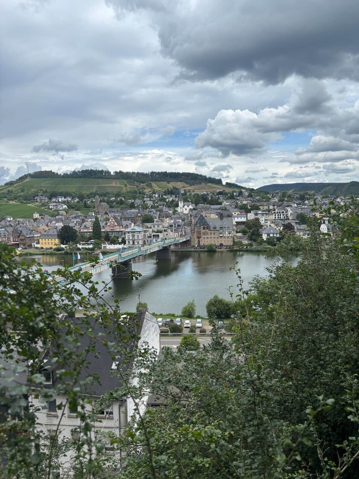 Un poble amb un riu, un pont i un turó al fons.