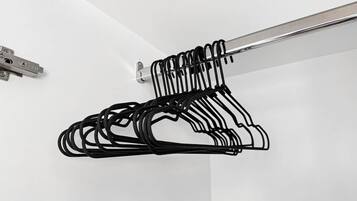 A metal hanger rack with multiple black hangers against a white wall.