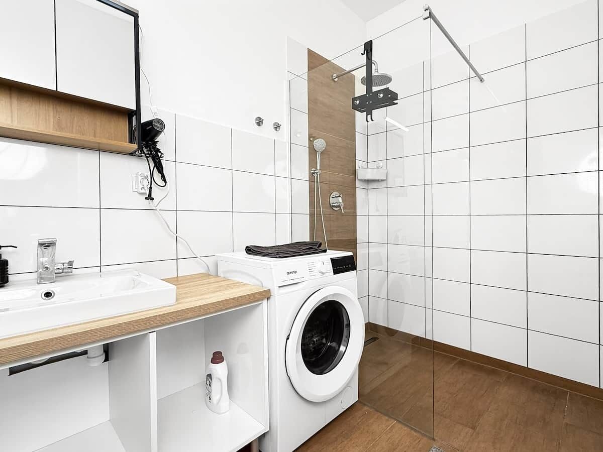 A modern bathroom with a sink, mirror, and a built-in washing machine.