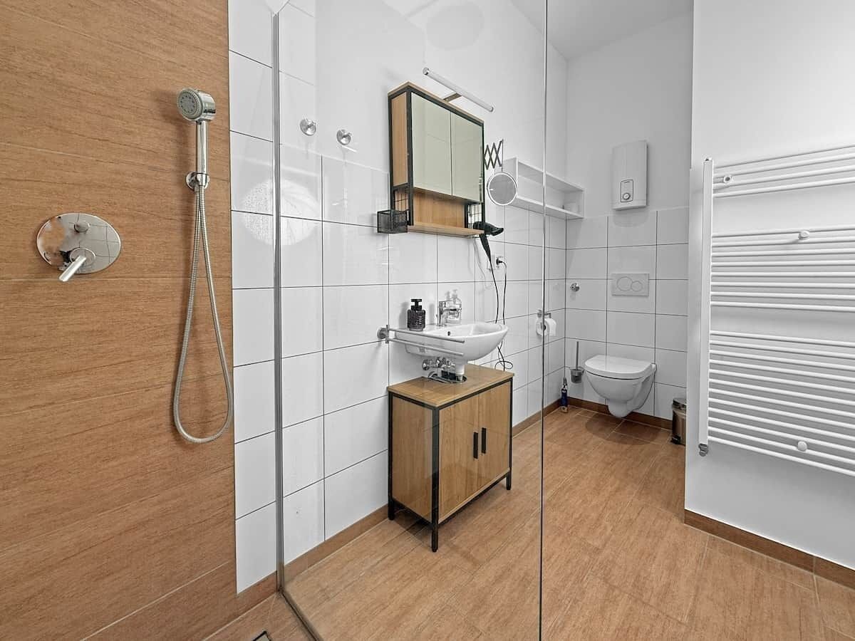 A modern bathroom with a shower, toilet, and sink.