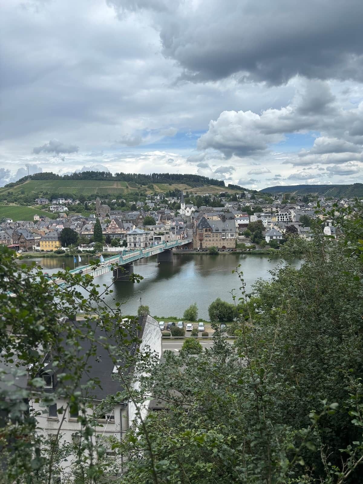 Une ville traversée par une rivière, avec un pont et des collines en arrière-plan.