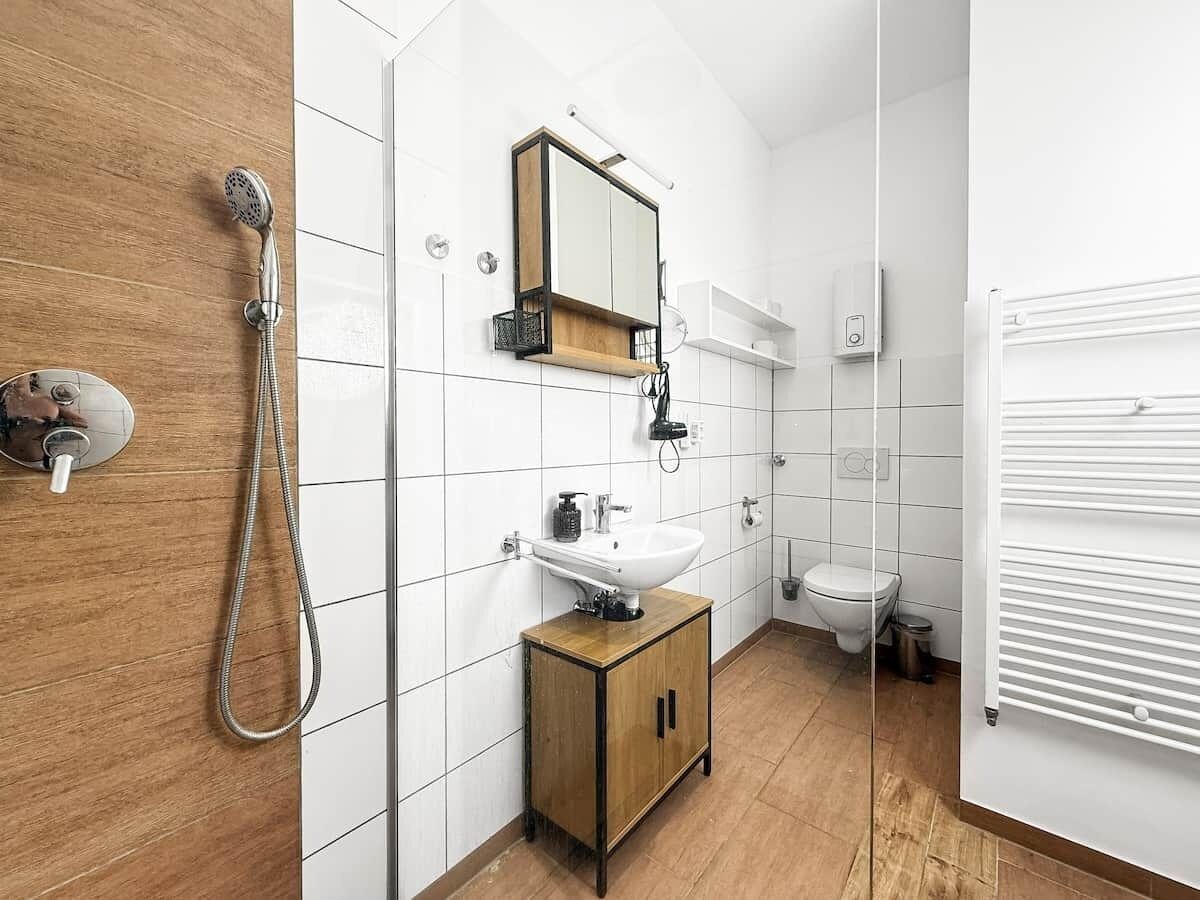 A modern bathroom with a shower, sink, mirror, and toilet.