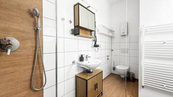 A modern bathroom with a shower, sink, mirror, and toilet.
