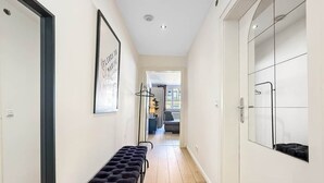A hallway with a bench, a framed sign, and a view into a room with a bed and a window. - Central & Cozy Loft Heart of Hannover Apartment (Hanover)