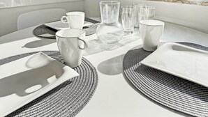 A dining table set with white plates, clear glasses, and a white mug, surrounded by woven placemats. - Central & Cozy Loft Heart of Hannover Apartment (Hanover)