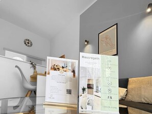 Moderni hotellihuone, jossa on lasipöytä, sohva ja seinällä oleva taulu.