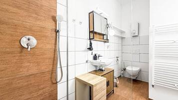 Een moderne badkamer met een houten wastafelmeubel, een glazen douchecabine en een wit toilet.