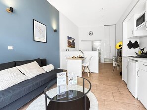Een moderne woonkamer met een bank, een salontafel en een eethoek met een witte tafel en stoelen.