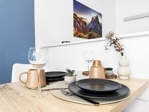 Een eettafel gedekt met borden, glazen en een vaas met bloemen.