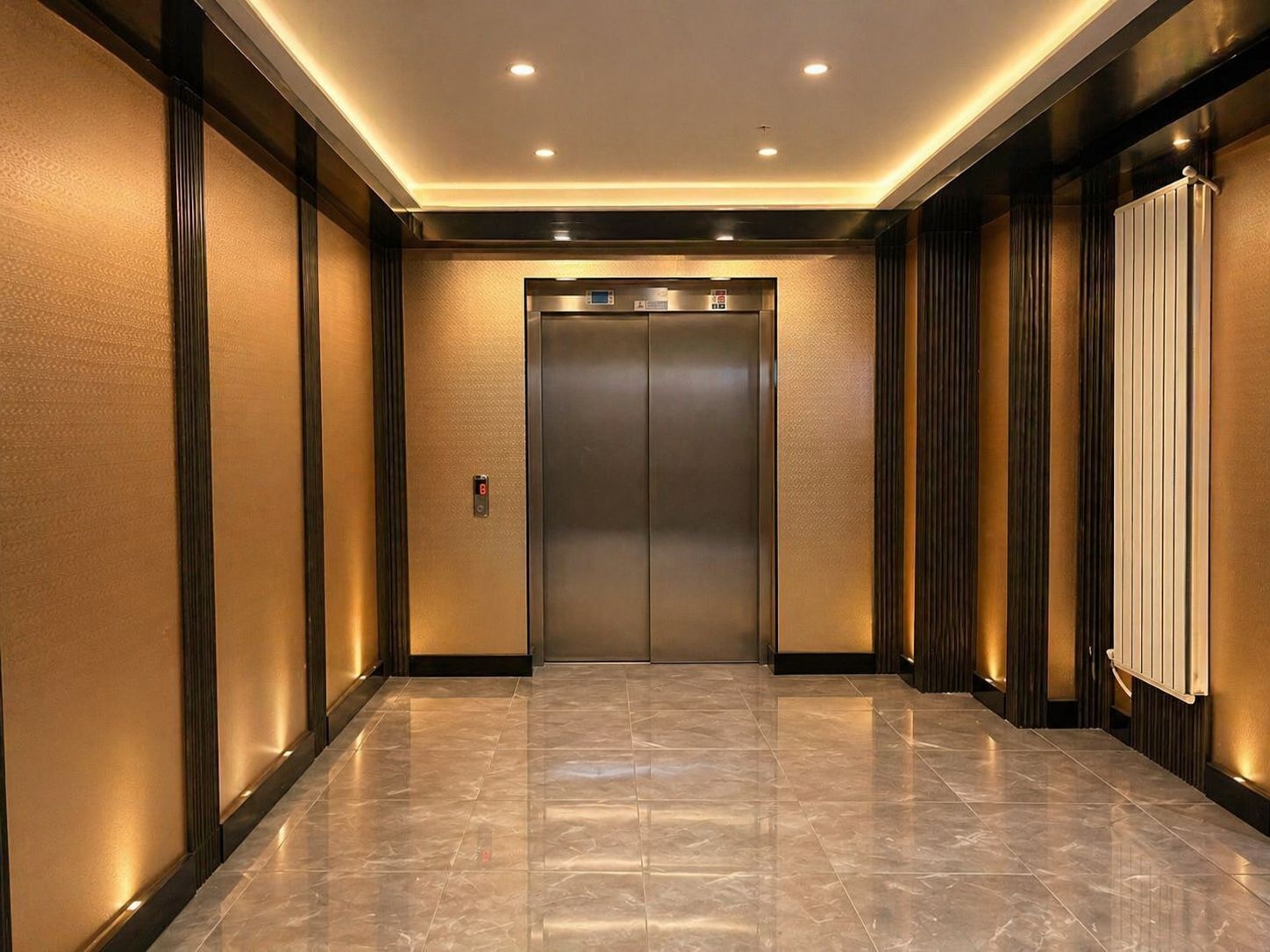 Un ascensor moderno con pantalla digital, piso de mármol y pared con líneas verticales.