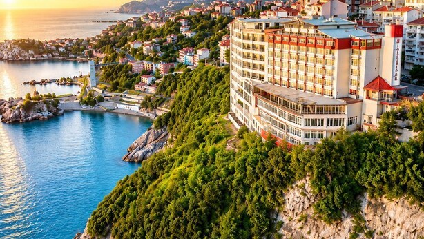 Hotel frente al mar, con vistas al océano, rodeado de vegetación y montañas al fondo.