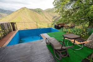Une piscine sur le toit offrant une vue sur les montagnes, une terrasse en bois et du mobilier d’extérieur.